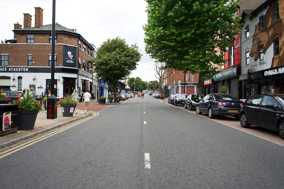 An aerial view of a small commercial street scene showing two shopfronts with signage: one for Thames Food & Wine and the other with a green awning. In front of the shops, there are several parked car